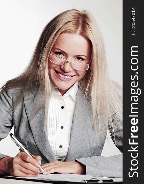 Business woman writing in notebook on a gray background