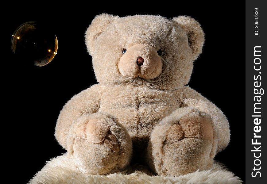 Plush teddy bear toy with bubble on black background