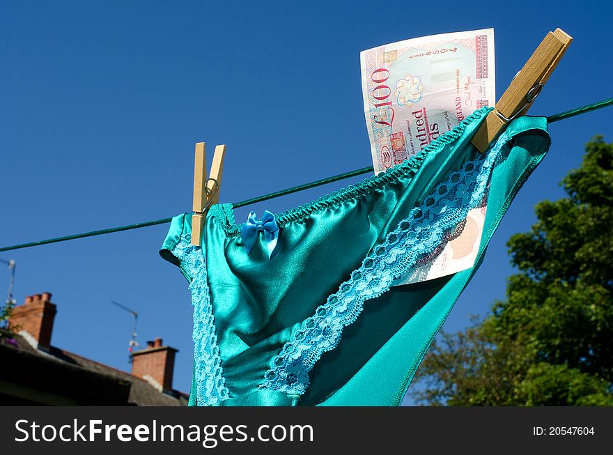 Silk and lace panties with a one hundred pound note sterling, on a respectable suburban washing line hinting at prostitution. Silk and lace panties with a one hundred pound note sterling, on a respectable suburban washing line hinting at prostitution.