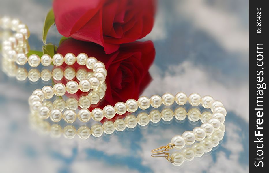 Elegant pearls over glass with clouds and rose very shallow depth of field. Elegant pearls over glass with clouds and rose very shallow depth of field