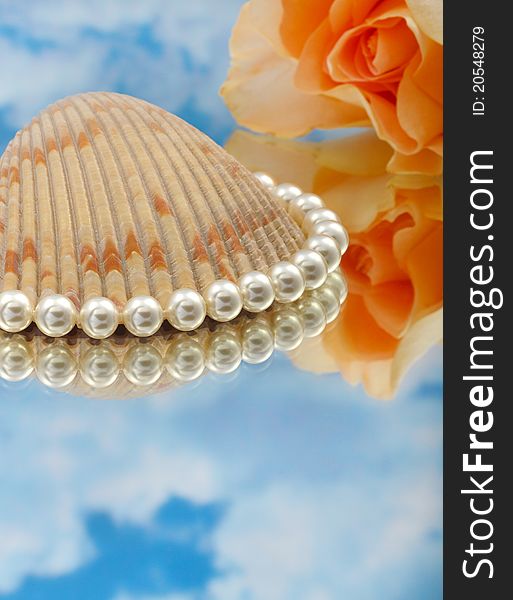 Elegant pearls over glass with clouds, shell, and rose very shallow depth of field