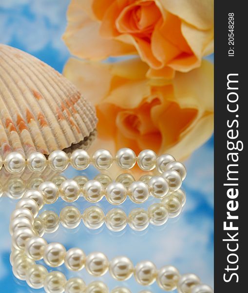 Elegant pearls over glass with clouds, shell, and rose very shallow depth of field. Elegant pearls over glass with clouds, shell, and rose very shallow depth of field