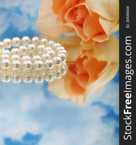 Elegant pearls over glass with clouds and rose very shallow depth of field