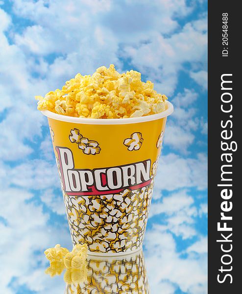 Popcorn on glass with cloud background and container
