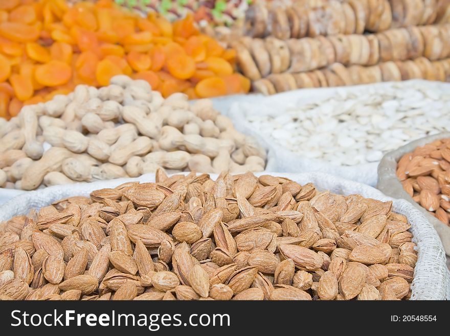 Natural unprocessed almonds in focus on foreground with unfocused nuts and dried fruit on backround. Natural unprocessed almonds in focus on foreground with unfocused nuts and dried fruit on backround