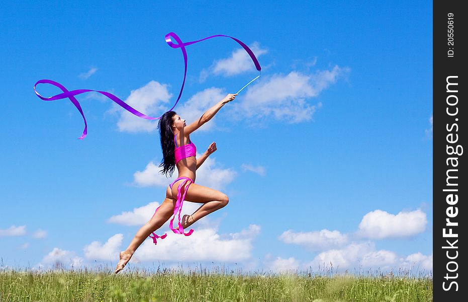 Happy jumping young woman with a ribbon outdoor on a summer day. Happy jumping young woman with a ribbon outdoor on a summer day