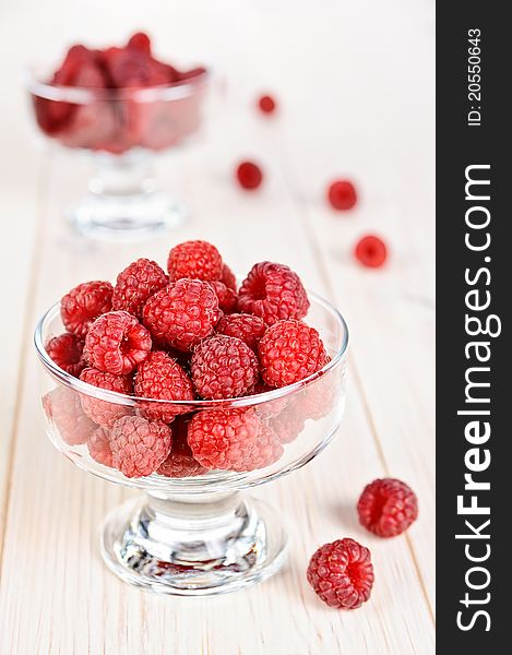 Raspberry in a small glass bowl on the light background