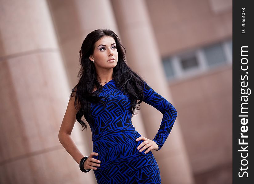 Very beautiful young brunette woman wearing a blue mini dress in the street. Very beautiful young brunette woman wearing a blue mini dress in the street