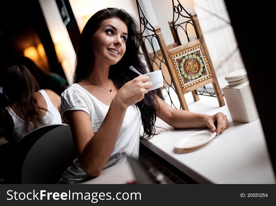 Beautiful dreamy young woman sitting in the cafe with a cup of coffee. Beautiful dreamy young woman sitting in the cafe with a cup of coffee