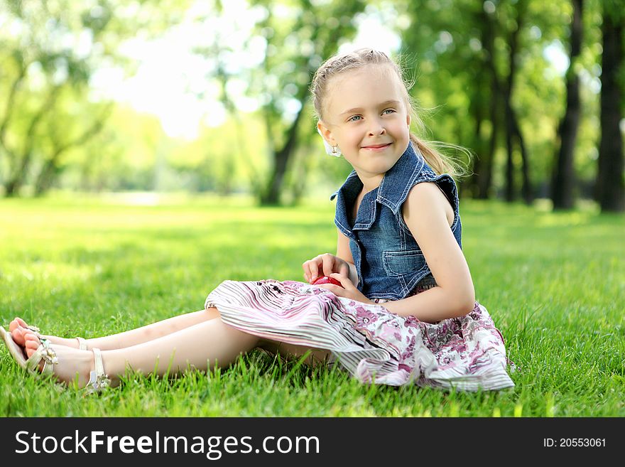 Portrait of a little girl sitting on the grass  in the park. Portrait of a little girl sitting on the grass  in the park