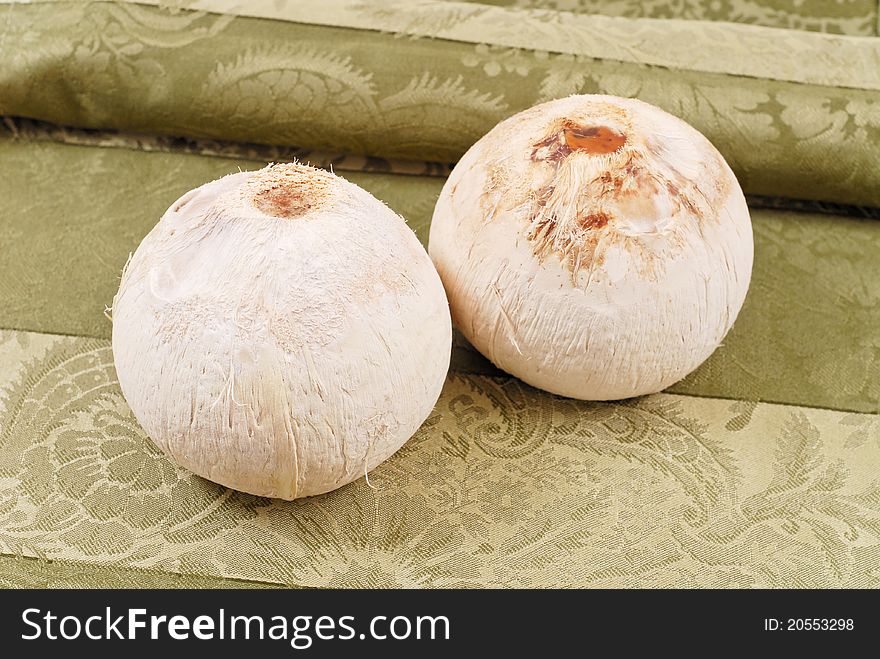 Two Whole Coconuts On Green Fabric