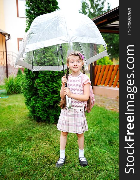 Brunette schoolgirl with backpack under umbrella on a rainy day. Brunette schoolgirl with backpack under umbrella on a rainy day