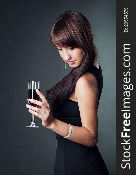 Portrait of young sexy woman wearing in the evening dress holding glass of wine