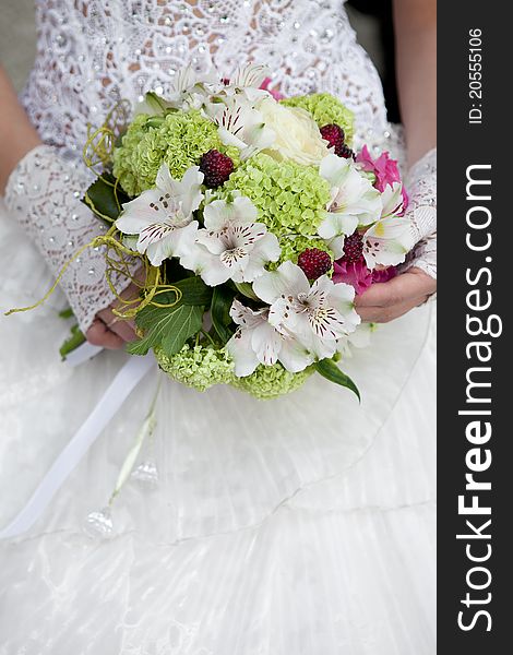 Wedding bouquet of white and green flowers at girl's hand