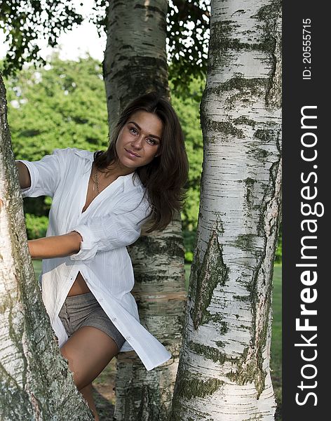 Cute girl in a white shirt standing near the birches. Cute girl in a white shirt standing near the birches