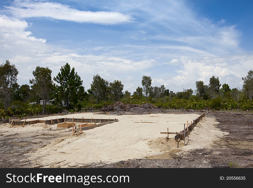 New Foundation, Footings. New construction site with wood framed foundations sand base. Blue sky and clouds in background