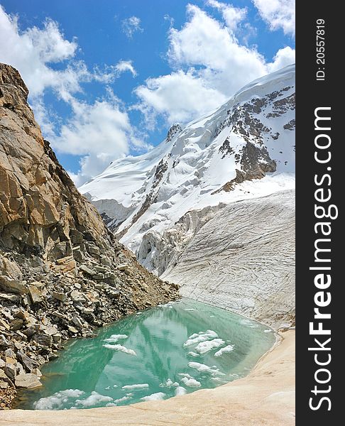 Mountain lake with ice, snow and clouds