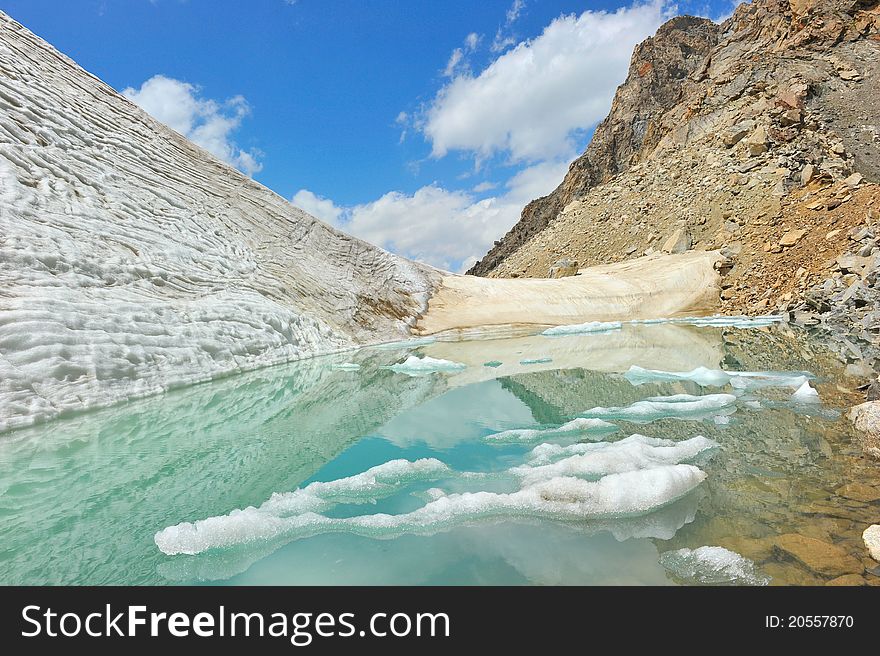 Mountain lake with ice, snow and clouds