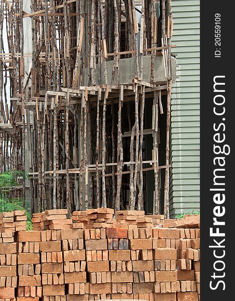A portrait of traditional wooden scaffolding on a construction site with stacks of brick.