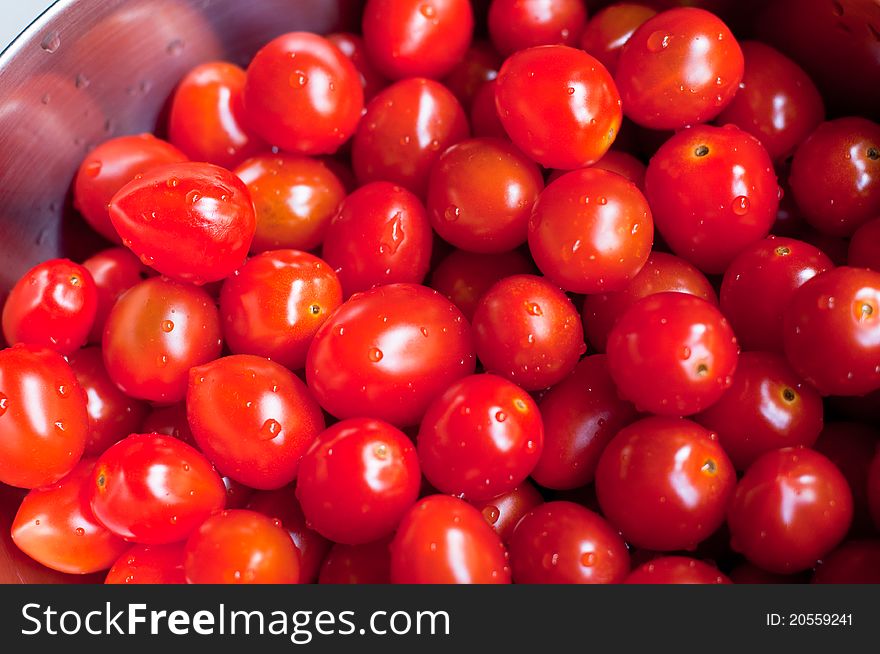 A bowl of washed fresh organic cherry tomatoes in a stainless steel bowl. A bowl of washed fresh organic cherry tomatoes in a stainless steel bowl