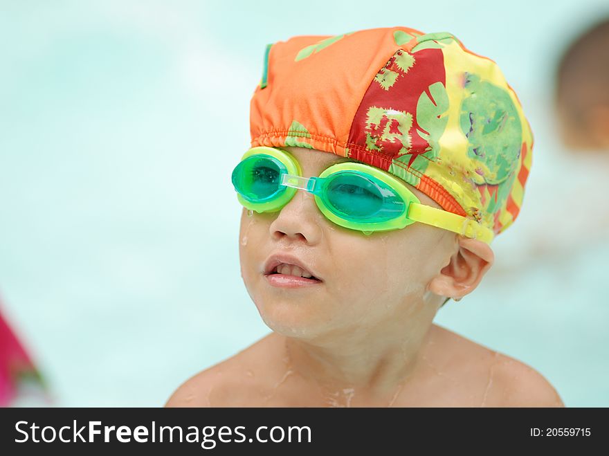 Four years old asian boy in swimming pool wearing swimming glasses.