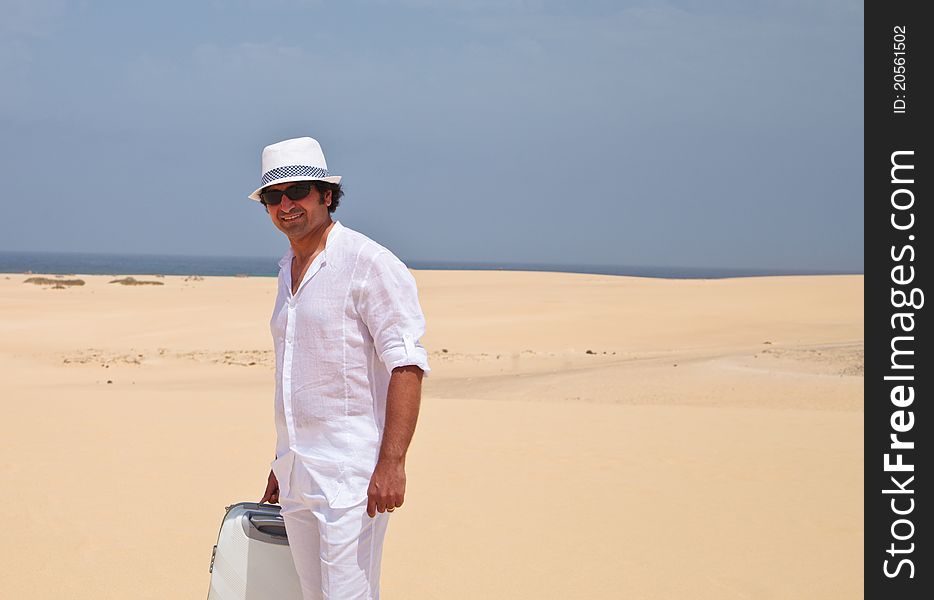 Man in white clothes walking on a beach and carrying luggage. Man in white clothes walking on a beach and carrying luggage