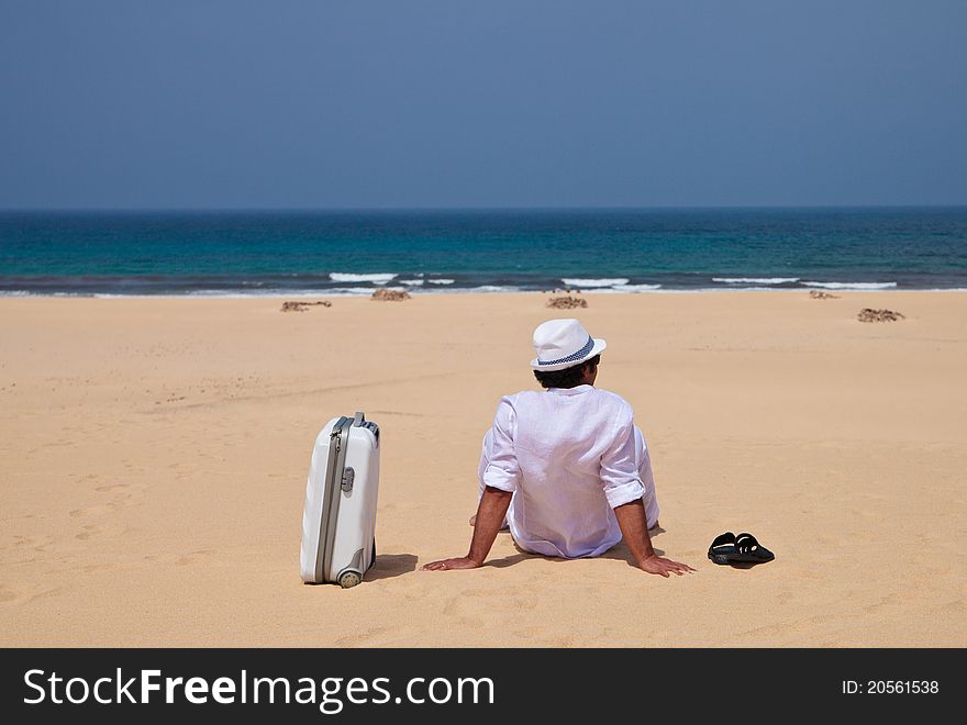 Man siting with luggage on a sand and observing sea. Man siting with luggage on a sand and observing sea