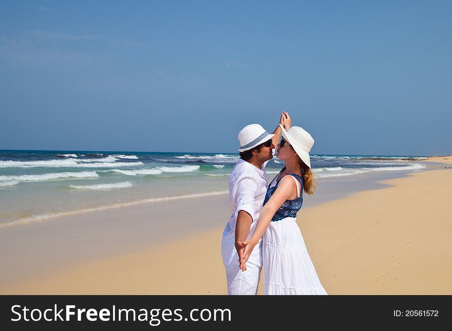 Couple in white clothes dancing on a beach