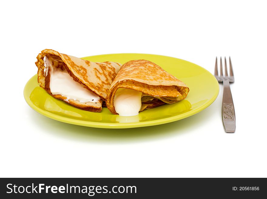 Pancakes with sour cream on green plate with fork. Pancakes with sour cream on green plate with fork