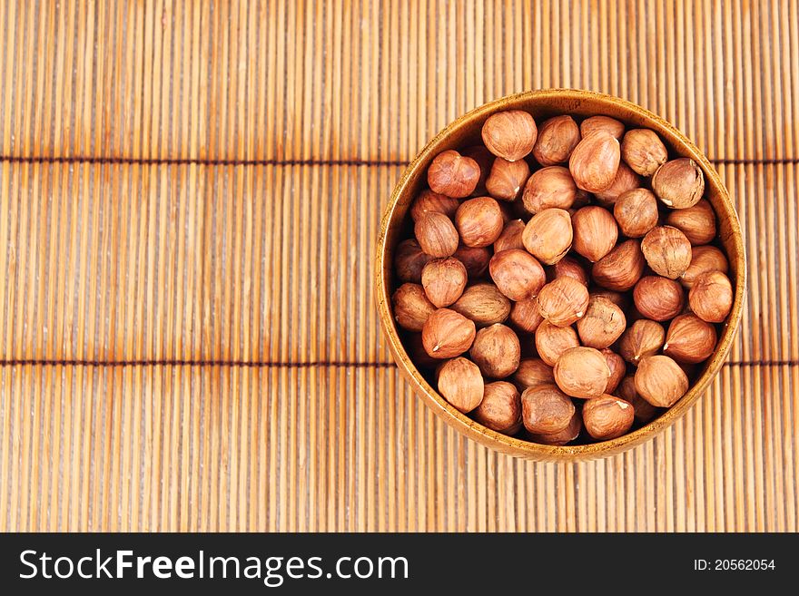 Hazelnut in a bowl on the background of a bamboo mat