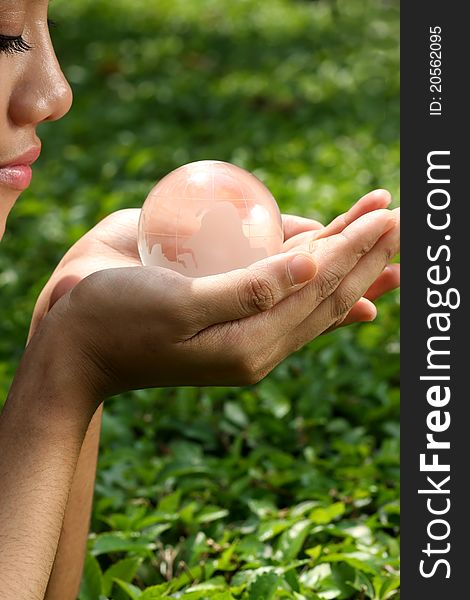 Woman face and hand with crystal globe in green leaves background