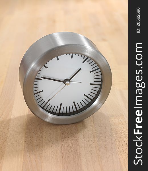 An analogue clock on a wooden bench