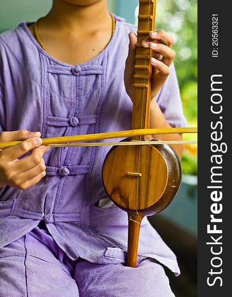 The boy plays a local Thai music instrument