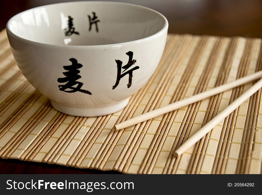 Chinese white bowl and sticks on bamboo mat. Chinese white bowl and sticks on bamboo mat