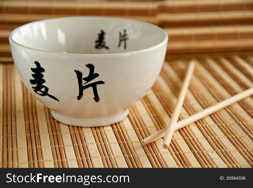 Chinese white bowl and sticks on bamboo mat. Chinese white bowl and sticks on bamboo mat