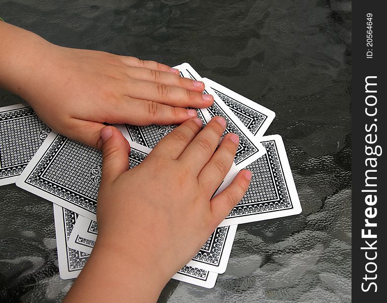 Closeup of two kid hands over a pile of playing cards. Closeup of two kid hands over a pile of playing cards