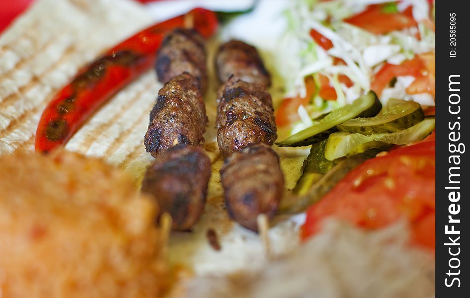 Traditional turkish shish kebab served on white plate with vegetables and lavash