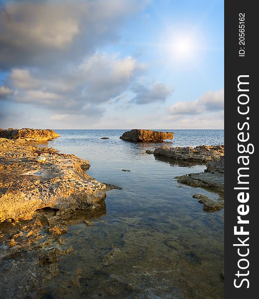 Stones into the sea on sunny sky background