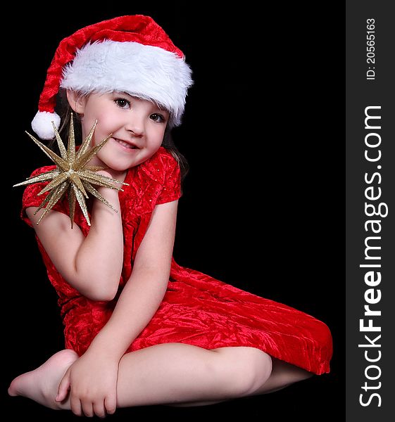 Pretty little girl in Santa hat posing with golden star. isolated on black. Pretty little girl in Santa hat posing with golden star. isolated on black