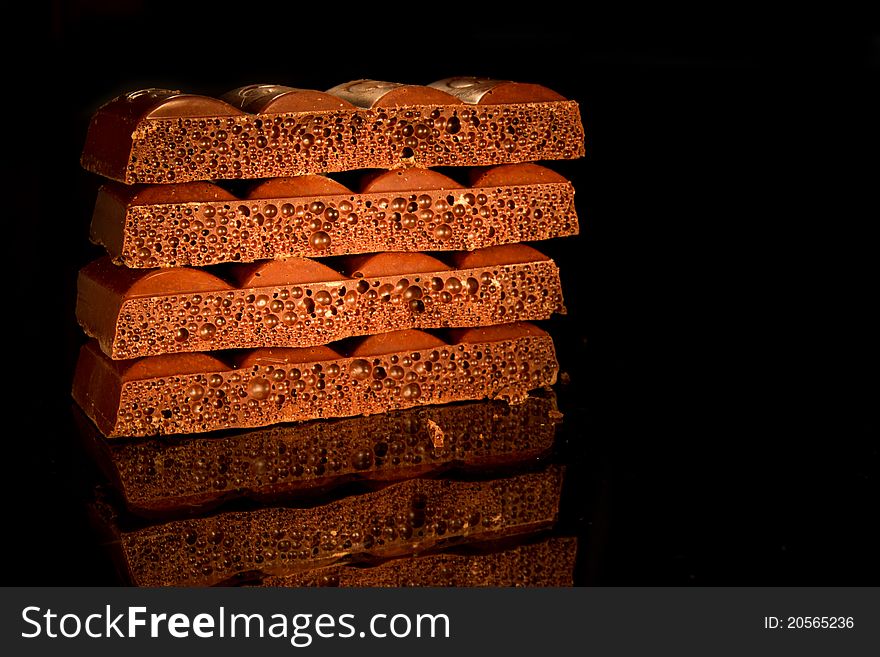 Pieces of black aerated chocolate on black background
