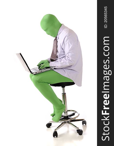 A green morph man in a dress shirt and tie sitting on a stool while working on his laptop. Isolated on white. A green morph man in a dress shirt and tie sitting on a stool while working on his laptop. Isolated on white.