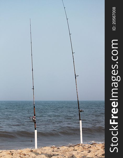 Fishing poles on the beach by the surf. Fishing poles on the beach by the surf