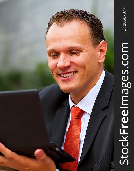 Portrait of happy smiling young businessman with a laptop