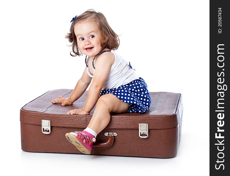 A little girl on the suitcase. Isolated on a white background