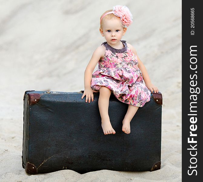 Little girl sitting on a suitcase in the desert. Little girl sitting on a suitcase in the desert