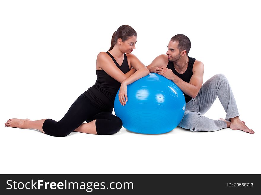 Sportive couple relaxing on fitball in gym isolated on white