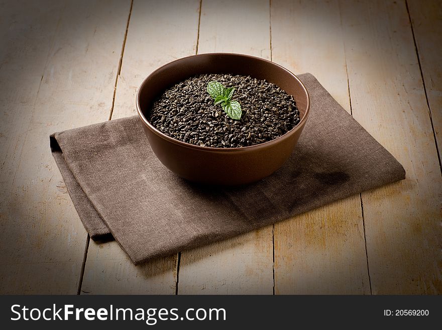 Photo of raw tea beans inside a bowl on wooden table with vignette. Photo of raw tea beans inside a bowl on wooden table with vignette