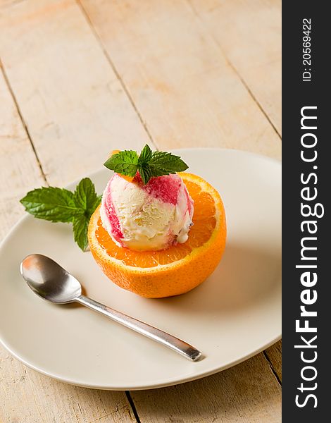 Photo of delicious fruity ice cream on cutted orang with fresh mint leaves. Photo of delicious fruity ice cream on cutted orang with fresh mint leaves