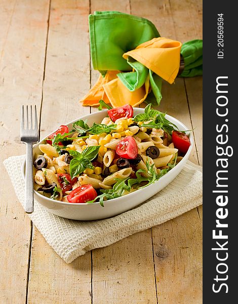 Photo of delicious tasty pasta salad on wooden table with fresh vegetables