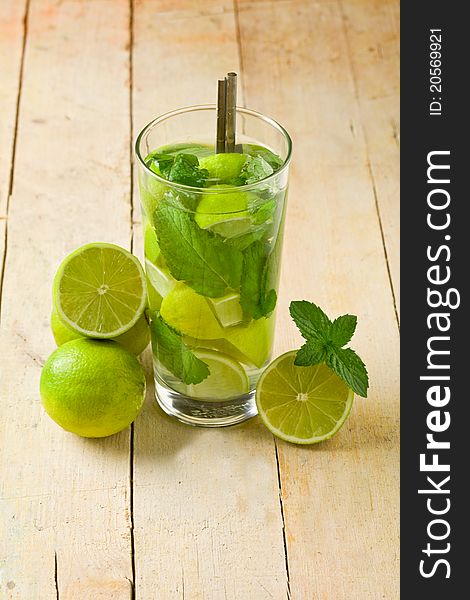 Photo of delicious mojito cocktail with cuttd lime on wooden table